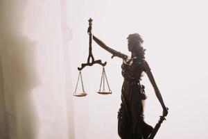 Justice and law concept.Male judge in a courtroom with the gavel, working with, computer and docking keyboard, eyeglasses, on table in morning light photo