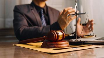 Justice and law concept.Male judge in a courtroom with the gavel, working with, computer and docking keyboard, eyeglasses, on table in morning light photo