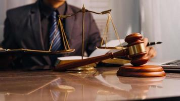 Justice and law concept.Male judge in a courtroom with the gavel, working with, computer and docking keyboard, eyeglasses, on table in morning light photo