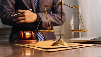 Justice and law concept.Male judge in a courtroom with the gavel, working with, computer and docking keyboard, eyeglasses, on table in morning light photo