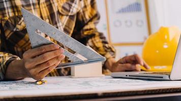 Dos colegas discutiendo el trabajo de datos y una tableta, un portátil con un proyecto arquitectónico en el sitio de construcción en un escritorio en la oficina foto