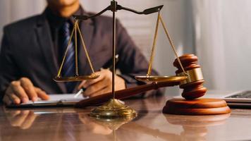 Justice and law concept.Male judge in a courtroom with the gavel, working with, computer and docking keyboard, eyeglasses, on table in morning light photo