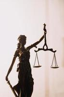 Justice and law concept.Male judge in a courtroom with the gavel, working with, computer and docking keyboard, eyeglasses, on table in morning light photo