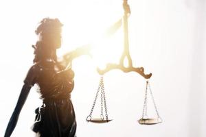 Justice and law concept.Male judge in a courtroom with the gavel, working with, computer and docking keyboard, eyeglasses, on table in morning light photo