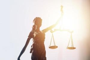 Justice and law concept.Male judge in a courtroom with the gavel, working with, computer and docking keyboard, eyeglasses, on table in morning light photo