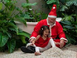 Santa Claus and cute little girl playing together at home photo