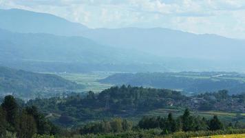 la cosecha de la vista del campo de arroz amarillo ubicada en el valle entre las montañas con el cielo nublado como fondo foto