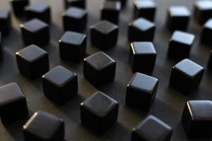 Black blocks on a dark background. Scattered cubes. Abstraction, field blur. Simplicity and elegance. Solidity, shine. photo