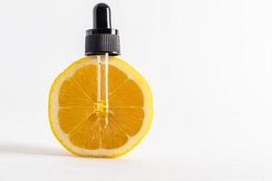 cosmetic glass pipette filled with natural lemon remedy on a vertical slice of ripe fruit. front view. close-up. space for text. photo