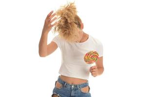 mujer rubia lamiendo dulces dulces. modelo femenino comiendo deliciosa paleta de confitería con expresión sorprendida. tiro del estudio aislado fondo blanco, foto