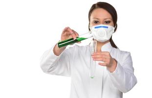 Female scientist holding two tubes transferring green liquid from one to another. Isolated on white background. photo