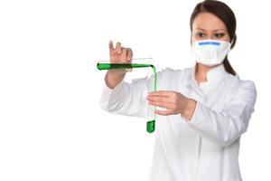 Female scientist holding two tubes transferring green liquid from one to another. Isolated on white background. photo