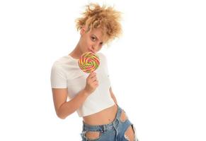 Blonde woman licking sweet candy. Female model eating delicious confectionery lollipop with surprised expression. studio shot isolated white background, photo