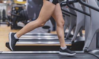 Young woman workout on treadmill in gym. Healthy lifestyle. Selective focus. Motion Blur. photo