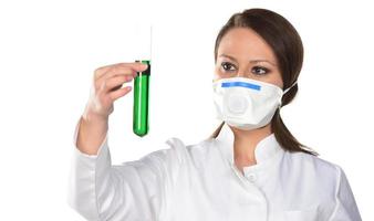 Scientist with white mask holding tube with green liquid. Isolated on white background. photo