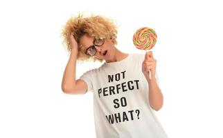 Blonde woman licking sweet candy. Female model eating delicious confectionery lollipop with surprised expression. photo