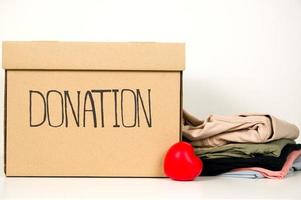 Closeup of donation box with stack of clothes near.Charity concept photo