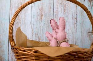 Closeup of pink toy bunnies in the basket full of colorfull eggs. Happy easter banner with place for text photo