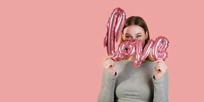 joven feliz mujer escondida detrás de amor balloon.st valentine's studio portrait.copyspace banner foto