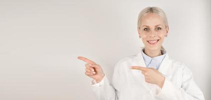 Young happy female doctor pointing at empty space.Medical banner with place for text photo