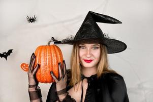 Autumn holidays banner with cute witch holding pumpkin on white background,. October 31 concept.Halloween party photo