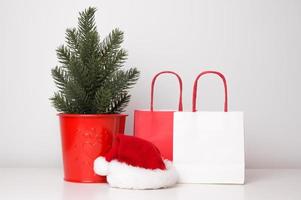 Christmas, new year sale or shopping concept. Paper bags near christmas tree and santa hat photo