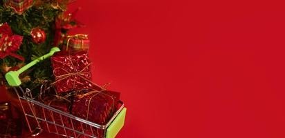 Christmas or new year shopping concept. Cart with presents near christmas tree with place for text. Mock up photo