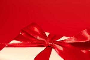 Gift box wrapped in white paper with a red bow. Place for text.Selective focus photo