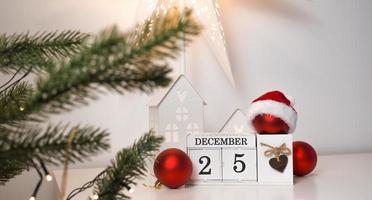 calendario vinytage con fecha del 25 de diciembre cerca del árbol de navidad y algunos adornos rojos foto