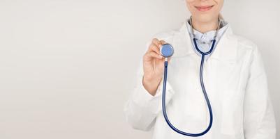 Female Doctor holding up the disc of a stethoscope pointing towards the camera preparing to listen to a patients heartbeat and lungs.Respiratory diseases concept.Copy space banner photo