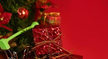 Closeup of Shopping cart full of gifts against red background near small christmas tree with place for text. Mockup photo