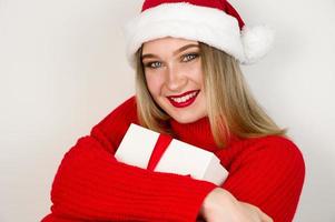 Christmas banner with place for text with pretty girl in santa hat and red sweater holding gift against white background photo
