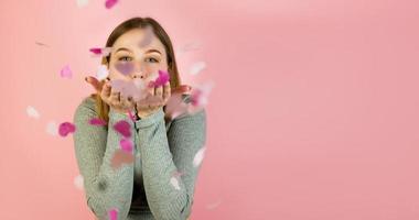 Studio portrait of a young happy female blowing heart shaped confetti. St Valentine's day concept copyspace banner photo
