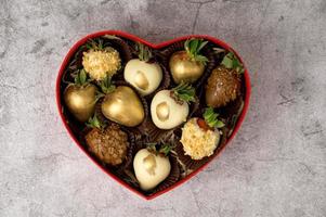 Flat lay. Heart shaped box with assorted chocolate covered strawberries on a gray background photo