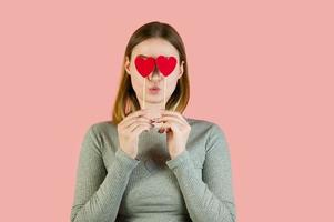 Blonde female with hearts against pink background. St Valentine's studio portrait photo