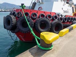 Protection of the side of the ship with car tires. Moored ship. Portholes in the hold. Ship at the pier. Equipment in the port photo