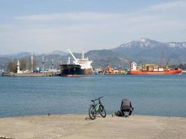 pescador en bicicleta en el muelle a la orilla del mar. un hombre está sentado en la playa con una caña de pescar. foto