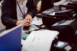 mano de empleado escribiendo cheque bancario en el mostrador. foto