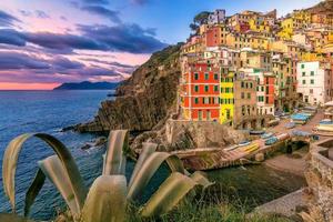 vista panorámica del pequeño pueblo de riomaggiore cinque terre en italia contra el cielo dramático al atardecer foto