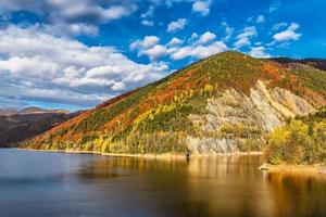 vista panorámica del bosque de colores otoñales que refleja el agua del lago en los alpes de transilvania foto