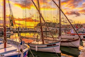 Scenic view of old fishing boats decorated with Christmas lights in the small port of Sanary sur Mer in south of France against dramatic golden winter photo