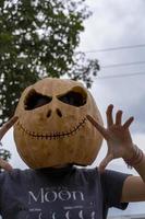 mujer joven con cabeza de calabaza después de cortarla y ponerle cara, halloween, foto