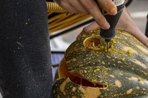 young man with a drill or dremel drilling a pumpkin for halloween photo