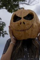 mujer joven con cabeza de calabaza después de cortarla y ponerle cara, halloween, foto