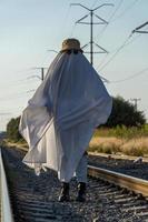 fantasma en el campo disfrutando del sol y el tren que pasa detrás, vías del tren foto