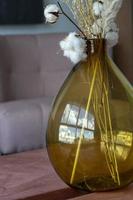 moderno y elegante arreglo de flores secas en un jarrón de vidrio con fondo marrón. foto