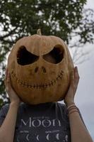 mujer joven con cabeza de calabaza después de cortarla y ponerle cara, halloween, foto