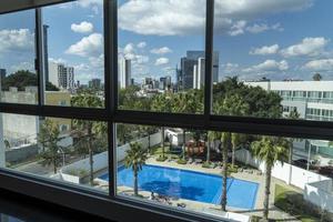 view of a swimming pool from an apartment up in a tower, view of buildings, trees and palm trees photo