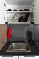 Different clean plates in dish drying rack on kitchen counter photo