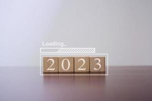 Loading new year 2023 with 2023 wooden blocks on table. Start the new year 2023 with a business goal plan. photo